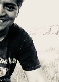 Portrait of young man standing on field against sky