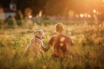 Rear view of woman with arms raised standing on field