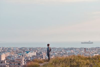 Side view of man standing against cityscape