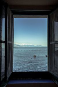 Scenic view of sea against clear blue sky seen through window