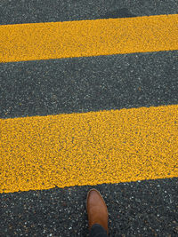 Low section of person standing on yellow road