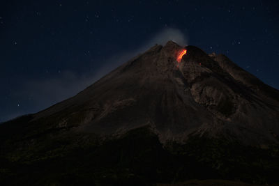 Low angle view of volcanic mountain against sky at night