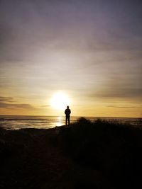 Silhouette man on beach against sky during sunset