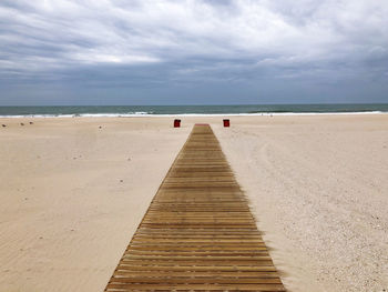 Pier on beach against sky