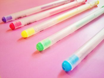 High angle view of colorful pens against pink background