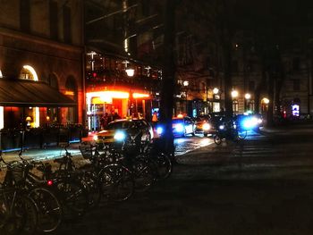 Cars parked on illuminated street by buildings in city at night
