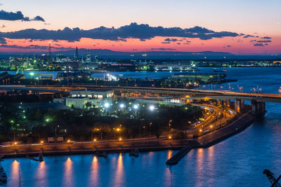 Illuminated city at waterfront during sunset