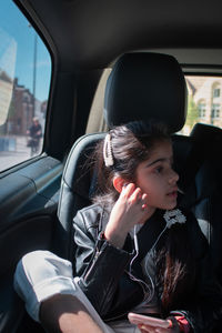 Young woman using mobile phone while sitting in car