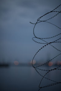 Close-up of fence against sky at sunset