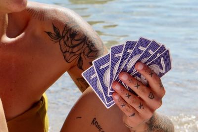 Close-up of shirtless young woman with hands on beach