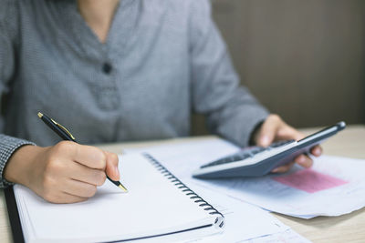 Midsection of person working with book on table