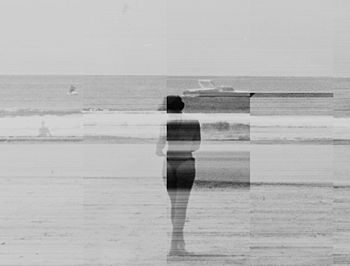 Rear view of woman standing on beach against sky