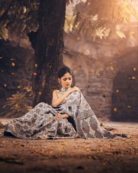 Woman sitting on tree trunk