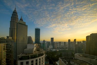 Modern buildings in city against sky during sunset