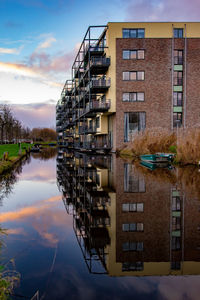 Reflection of building on river against sky