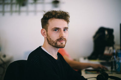 Portrait of young businessman sitting at desk in office