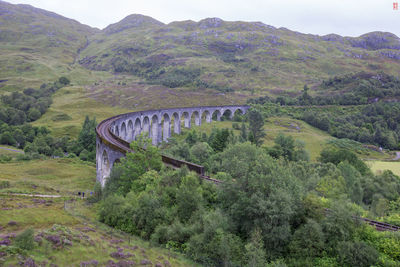 Arch bridge over landscape against mountain