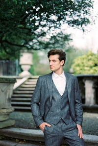 Portrait of young man standing against railing