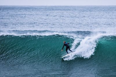 Man surfing in sea against sky