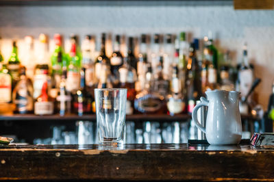 Drinking glass and jar on bar counter