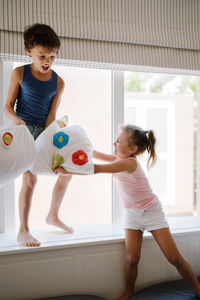 Brother and sister playing at home pillow fight