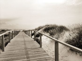 Footbridge over sea against clear sky