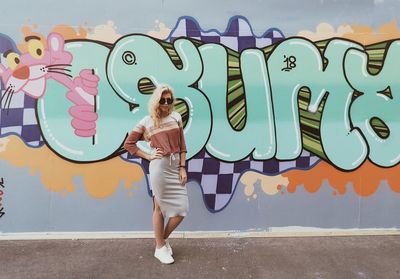 Full length of woman standing against graffiti wall
