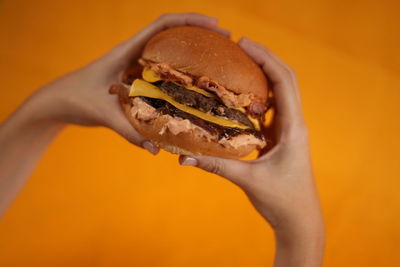 
hands of a young man taking a beef burger with cheddar cheese