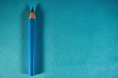 Close-up of colored pencils on blue table against wall