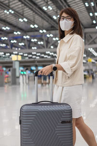 Woman holding umbrella standing at airport