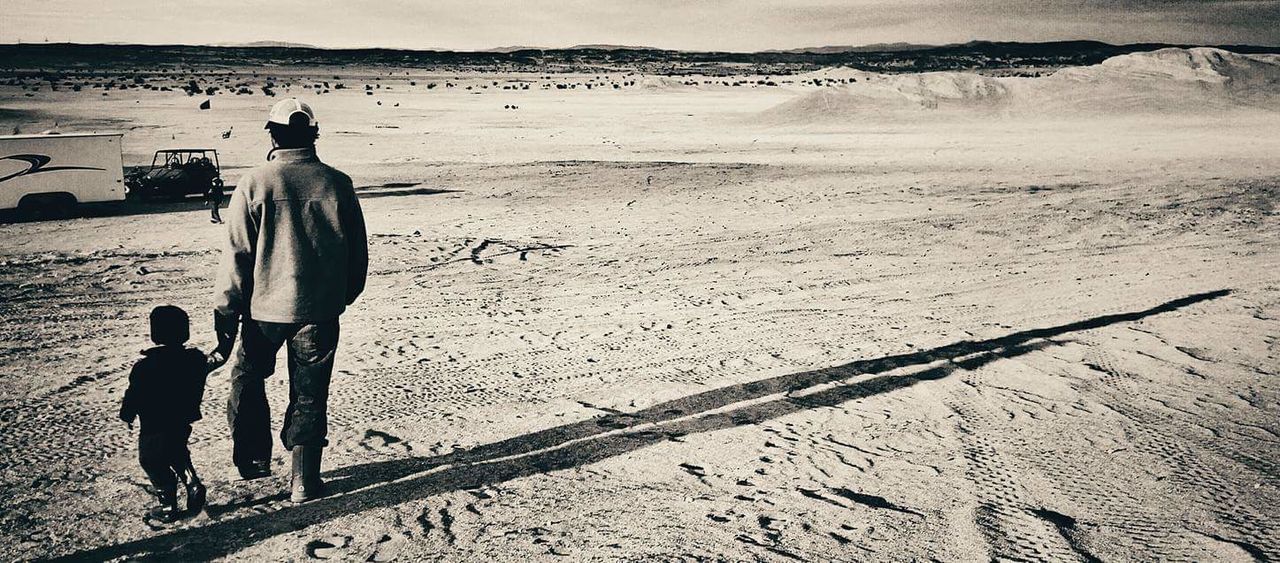 REAR VIEW OF FRIENDS STANDING ON DESERT