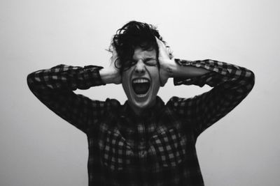 Young woman screaming against gray background