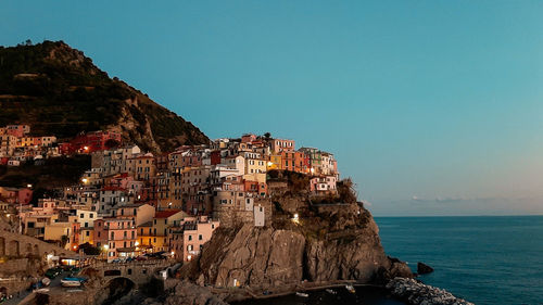 Buildings by sea against clear sky