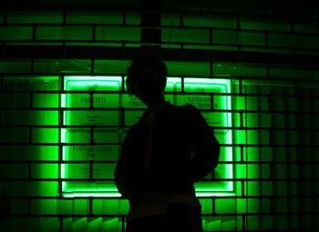 Rear view of silhouette man standing against illuminated wall