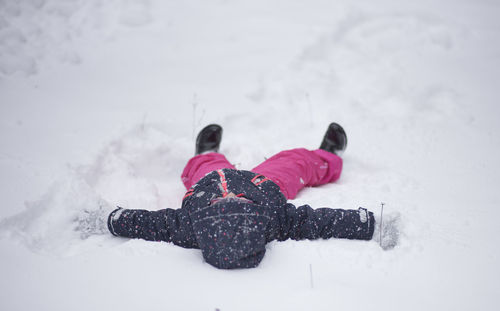 Close-up of girl lying on snow