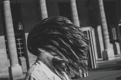 Close-up of woman tossing hair against building