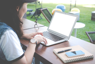 Midsection of woman using mobile phone while sitting on table