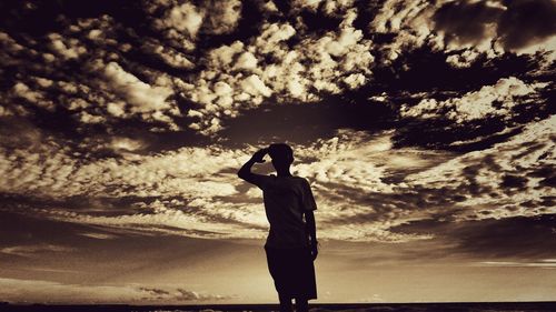 Side view of silhouette woman standing against sky during sunset