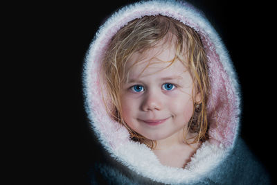 Close-up portrait of a cute girl against black background