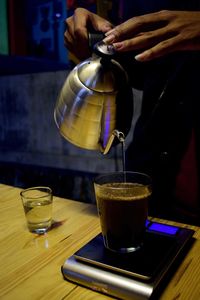 Midsection of man holding coffee on table