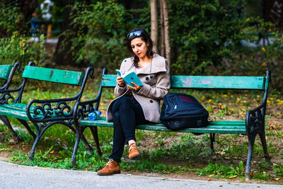 Portrait of young woman sitting on bench in park