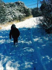 Rear view of man walking on snow covered land