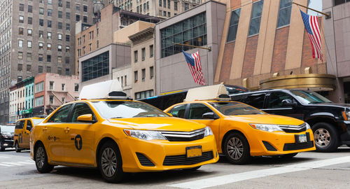 Yellow car on city street by buildings