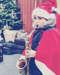 Portrait of girl wearing santa hat playing saxophone