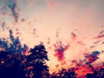 Low angle view of silhouette trees against dramatic sky