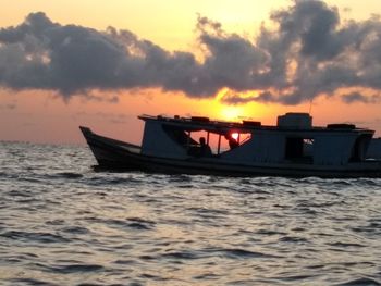 Boat sailing on sea against sky during sunset