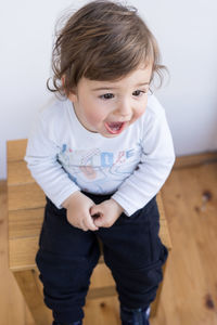 High angle view of cute boy sitting on stool at home