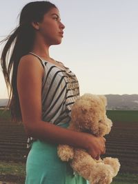 Thoughtful woman holding teddy bear standing at farm