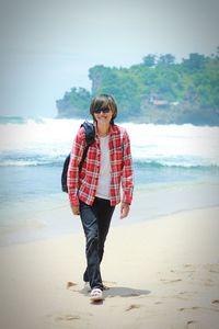 Full length of man standing at beach against sky