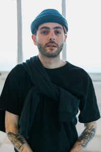 Portrait of young man standing against window